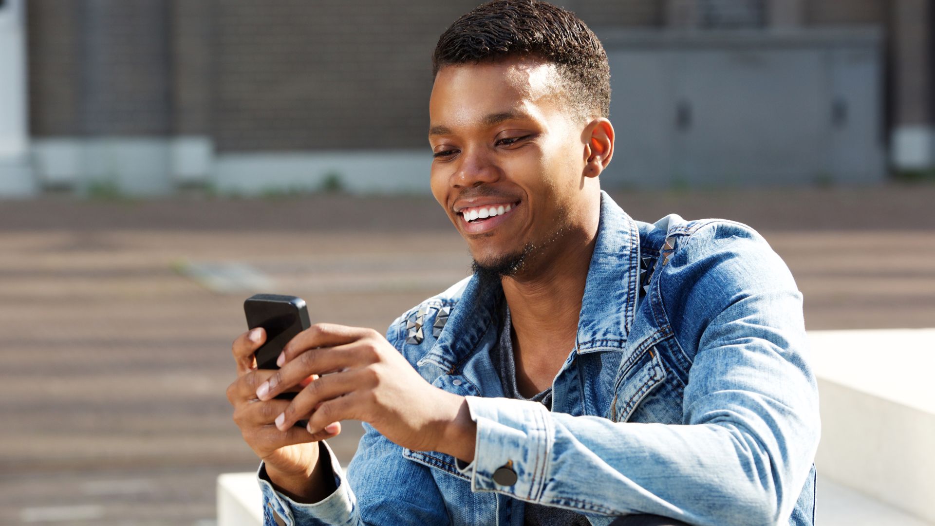 Homem utilizando o celular e sorrindo.