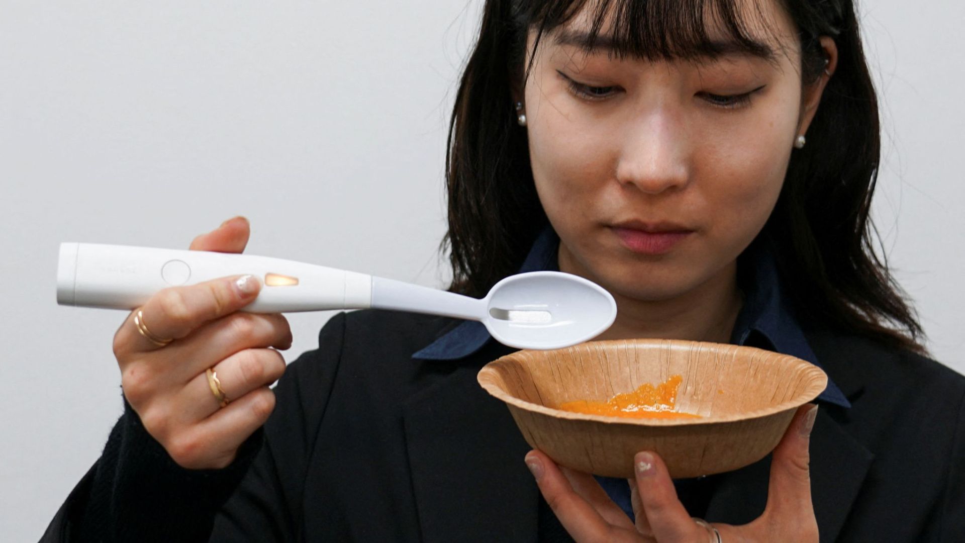 Na foto uma mulher asiática, consome um alimento utilizando a Electric Salt Spoon. Adeus sal, Olá tecnologia! Foto: Reuters